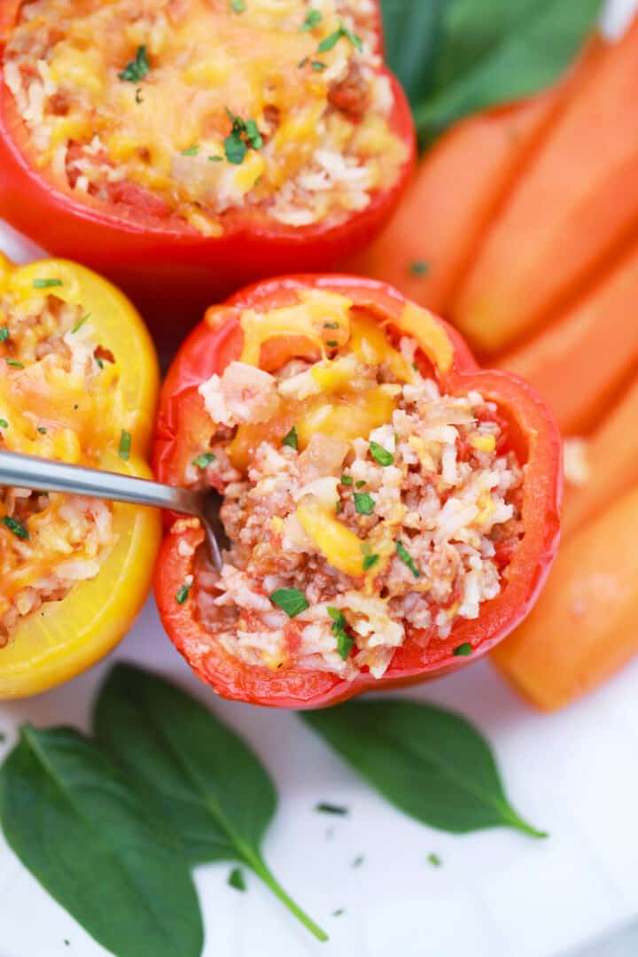 scooping the insides out with metal spoon of stuffed peppers