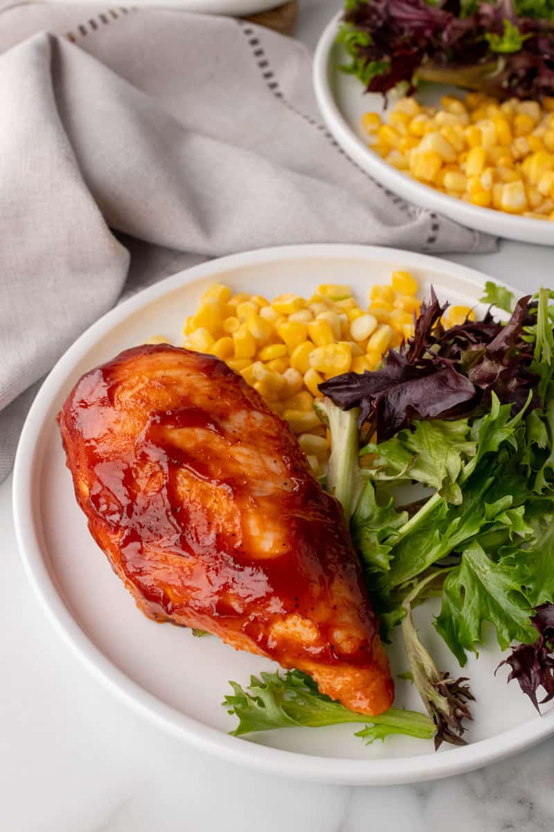 baked BBQ chicken on white plate with corn and salad
