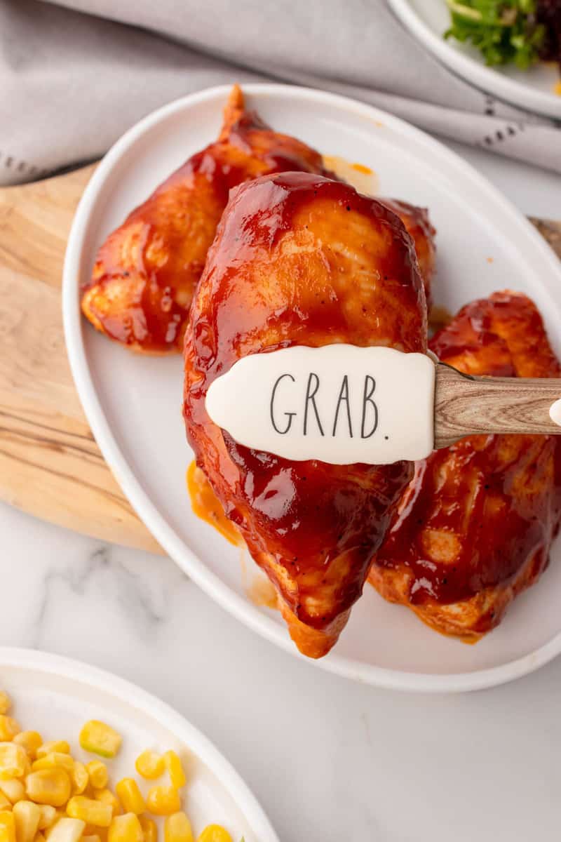 serving the BBQ chicken onto a white plate.