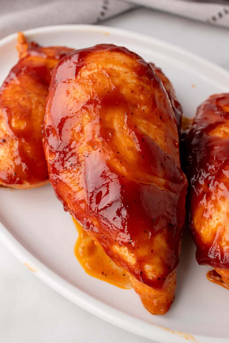 closeup of BBQ chicken on white serving plate.