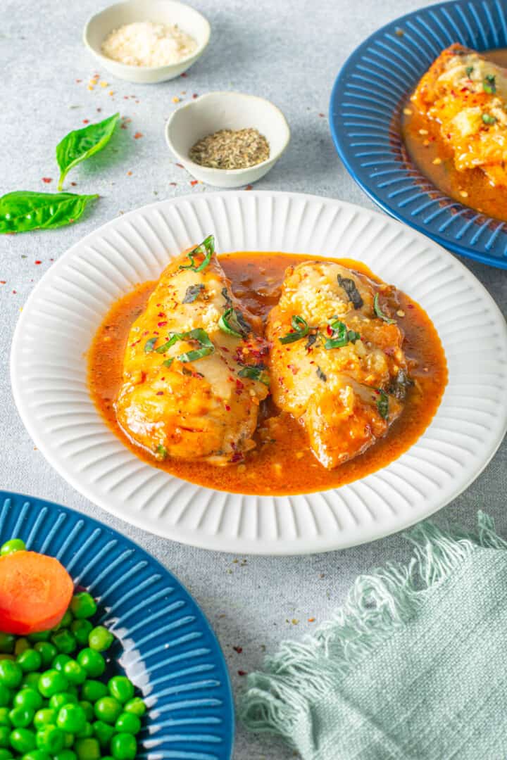 chicken parmesan on white plate covered in sauce