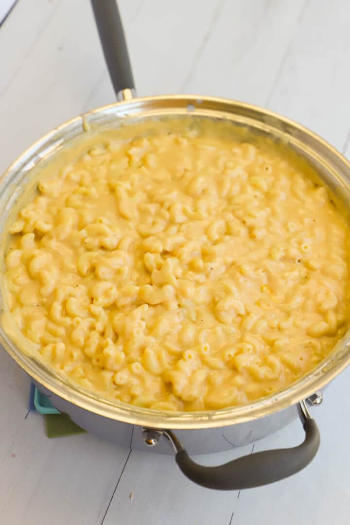 mixing together the noodles with the cheese sauce