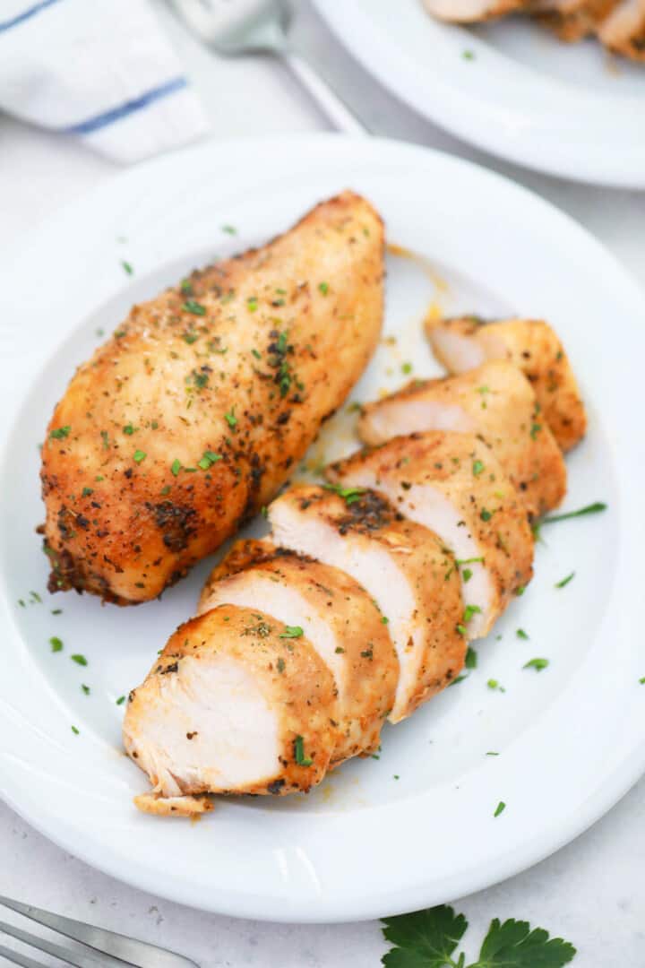 baked chicken breasts on white plate sliced.