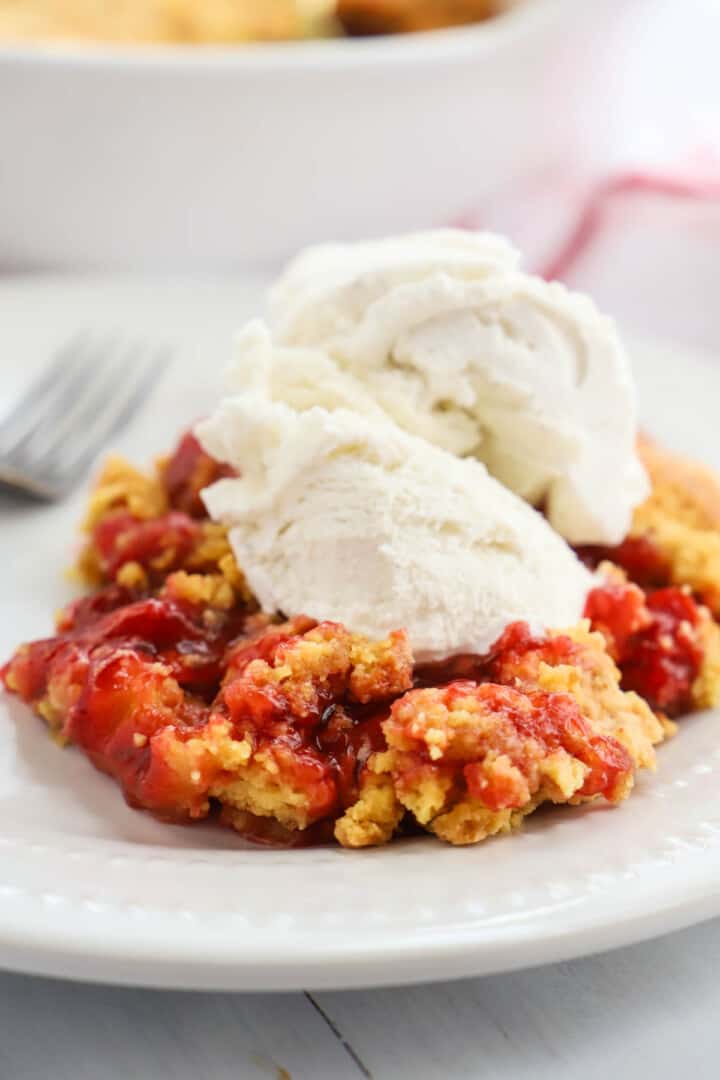 Cherry Dump Cake on white plate topped with vanilla ice cream