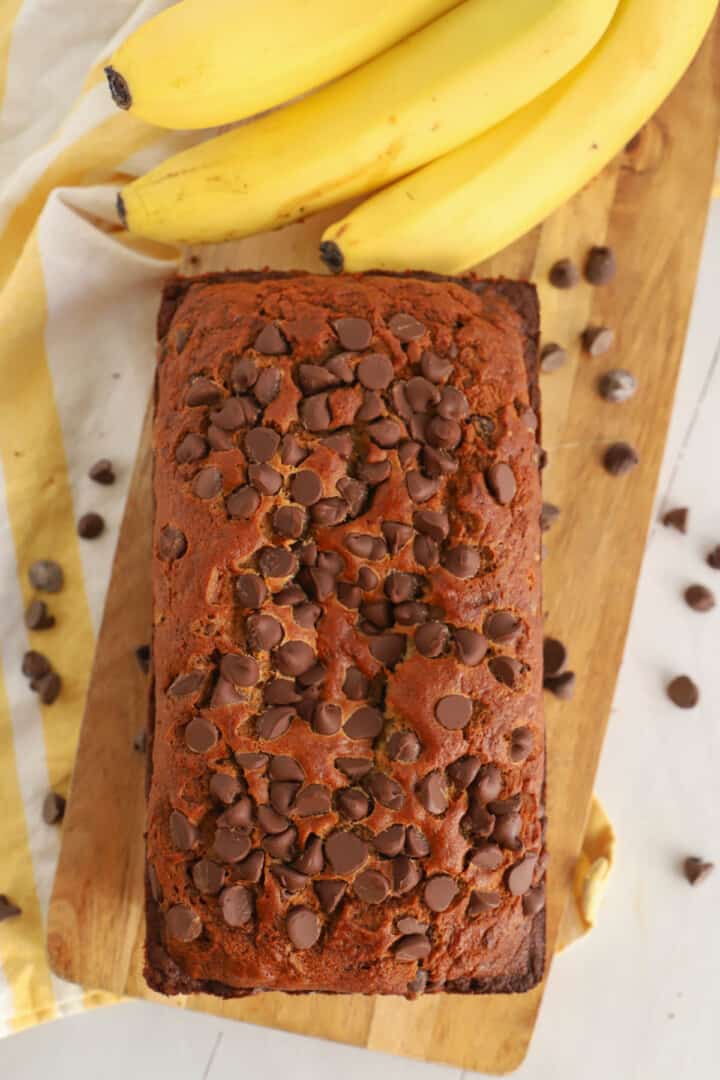 Chocolate Chip Banana Bread on wooden serving board with bananas in background