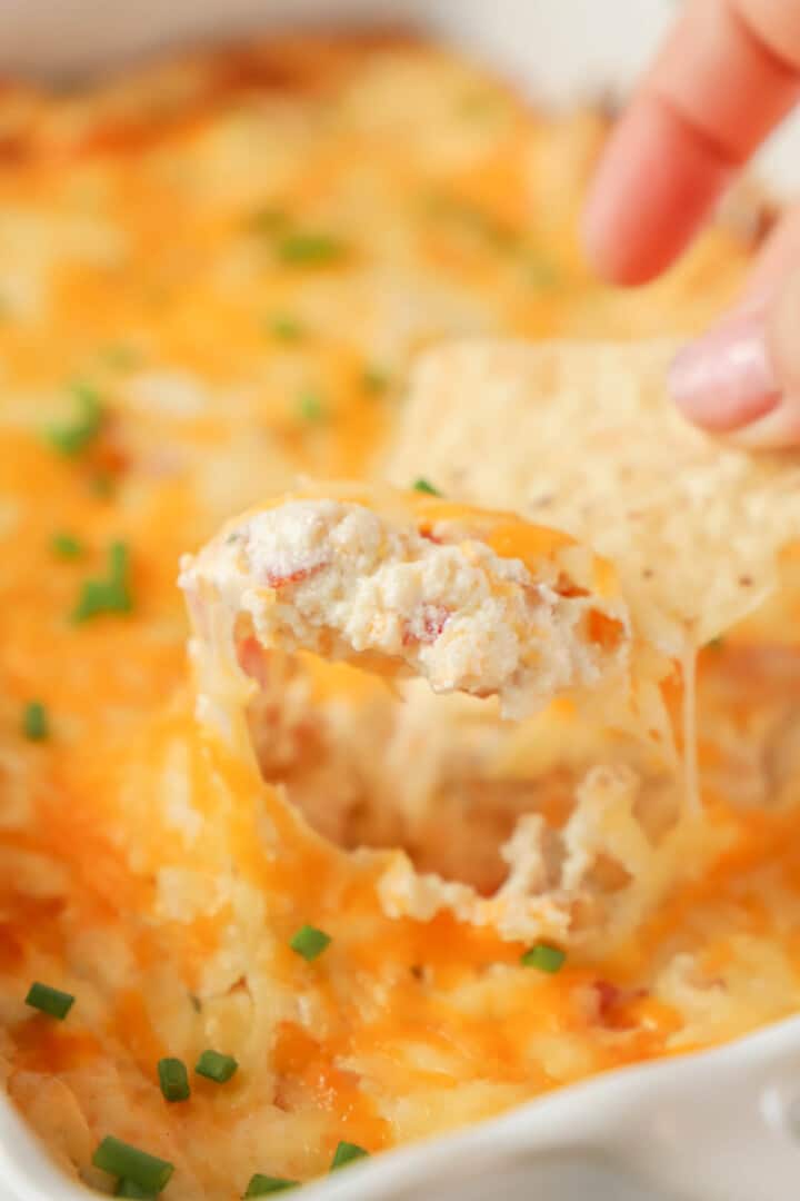 Crack Chicken Dip in casserole dish scooped out by a tortilla