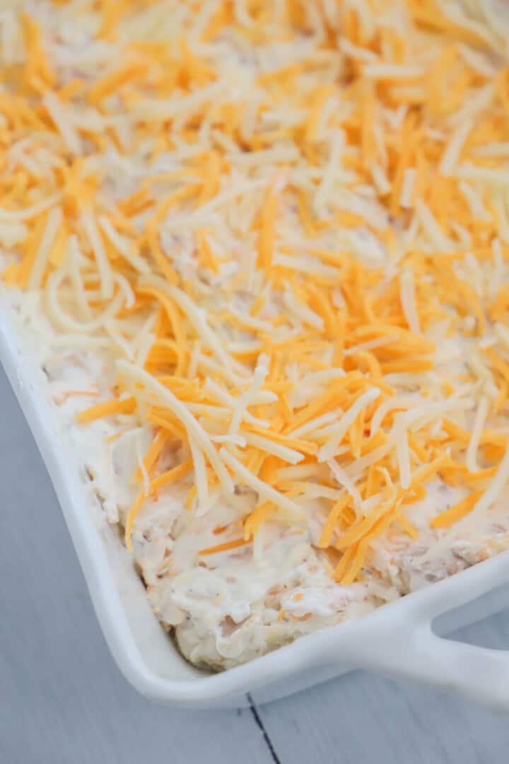 crack chicken dip in casserole dish topped with shredded cheese