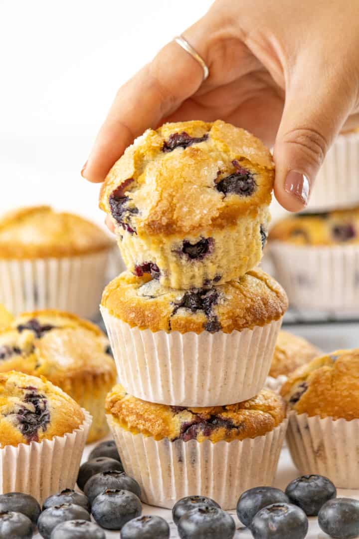 stacked lemon blueberry muffins and one in hand