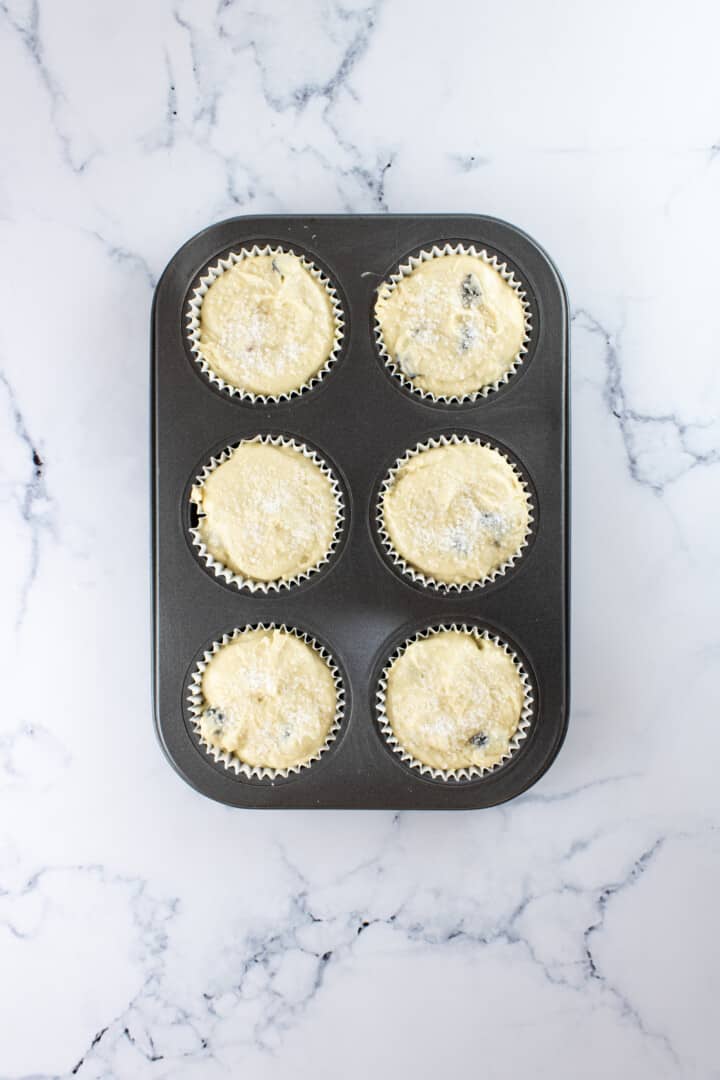 adding batter to the muffin cups in the muffin pan