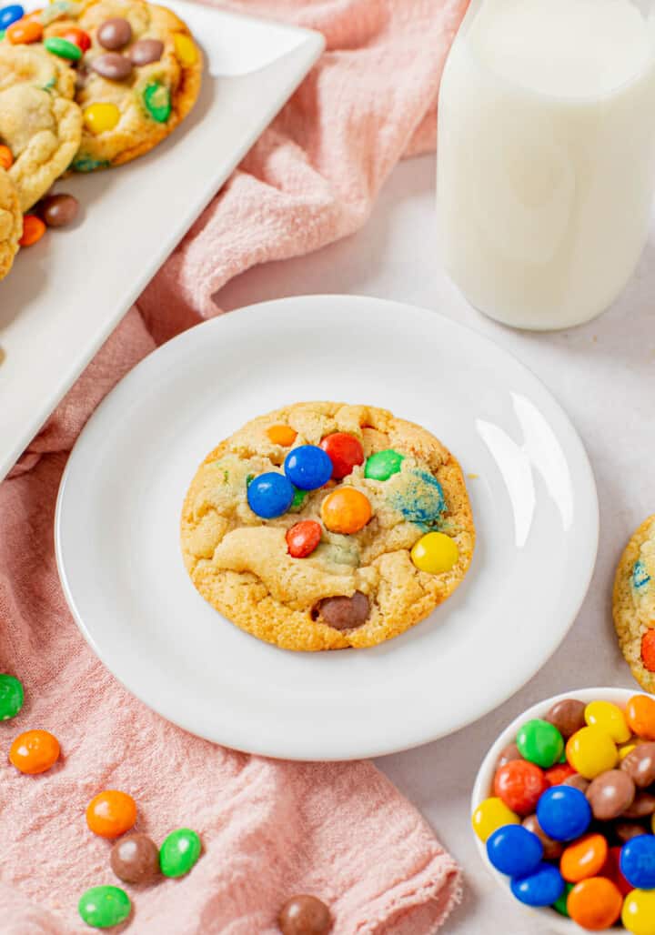 close up of single M&M cookie on white plate