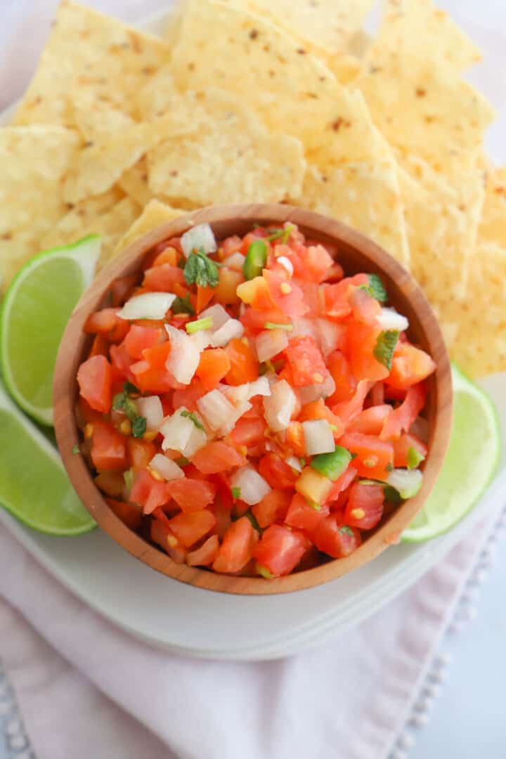top view of Pico de Gallo on white plate with tortilla chips and limes