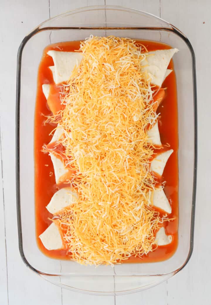topping enchiladas in casserole dish with cheese