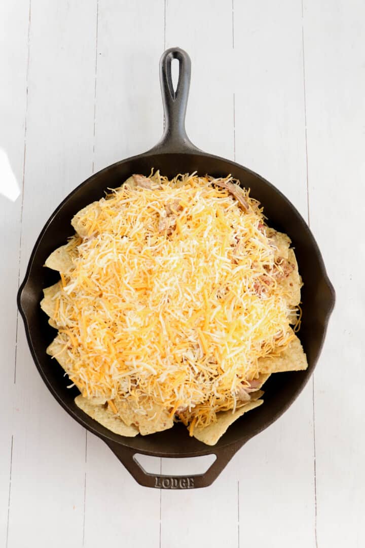 shredded cheese on top of pulled pork and tortilla chips
