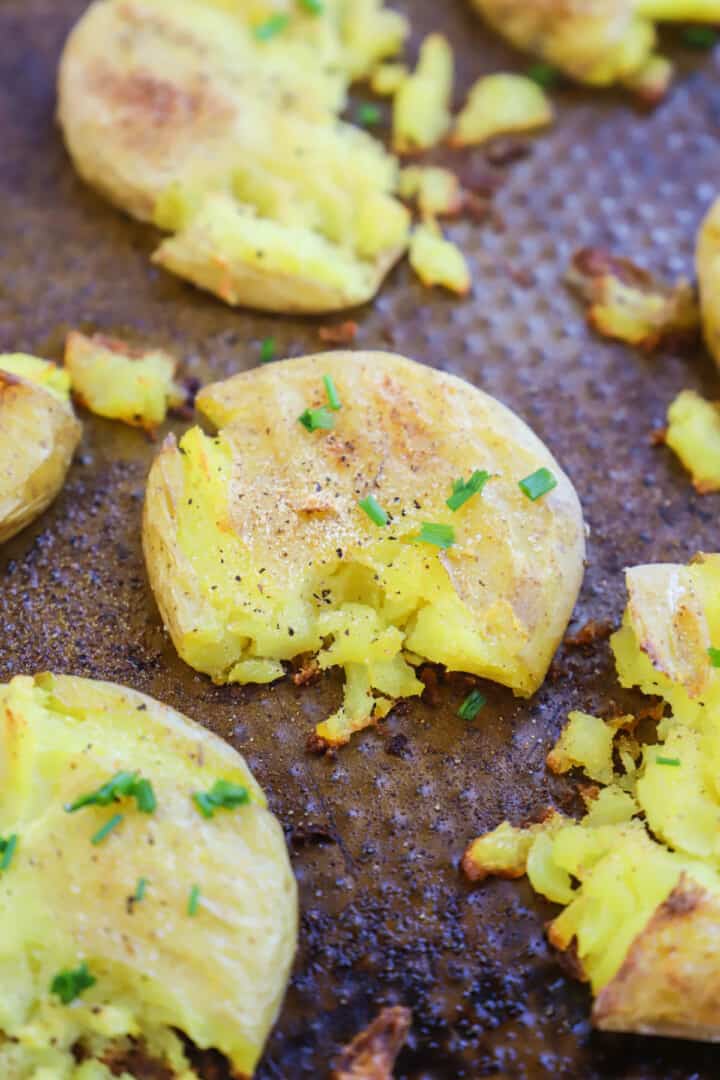 topping baked smashed potatoes with chives and serving