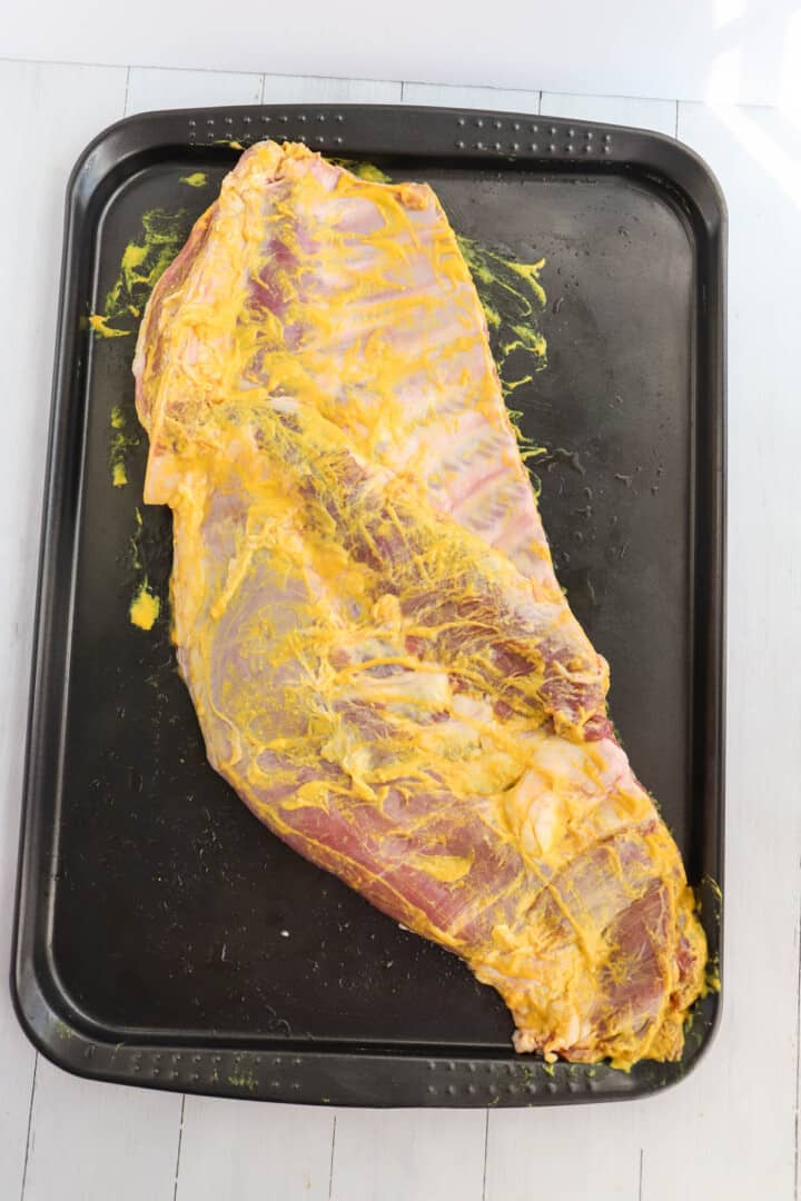 yellow mustard spread over pork ribs as binder