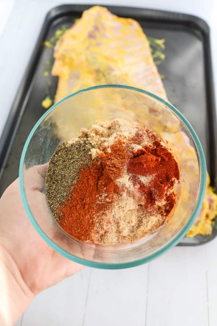 closeup of seasoning in glass bowl with ribs in background