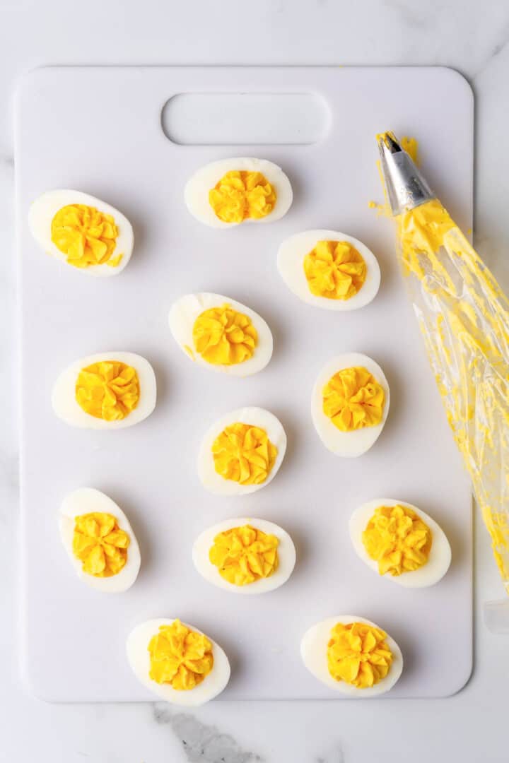 using a piping bag to fill the deviled eggs