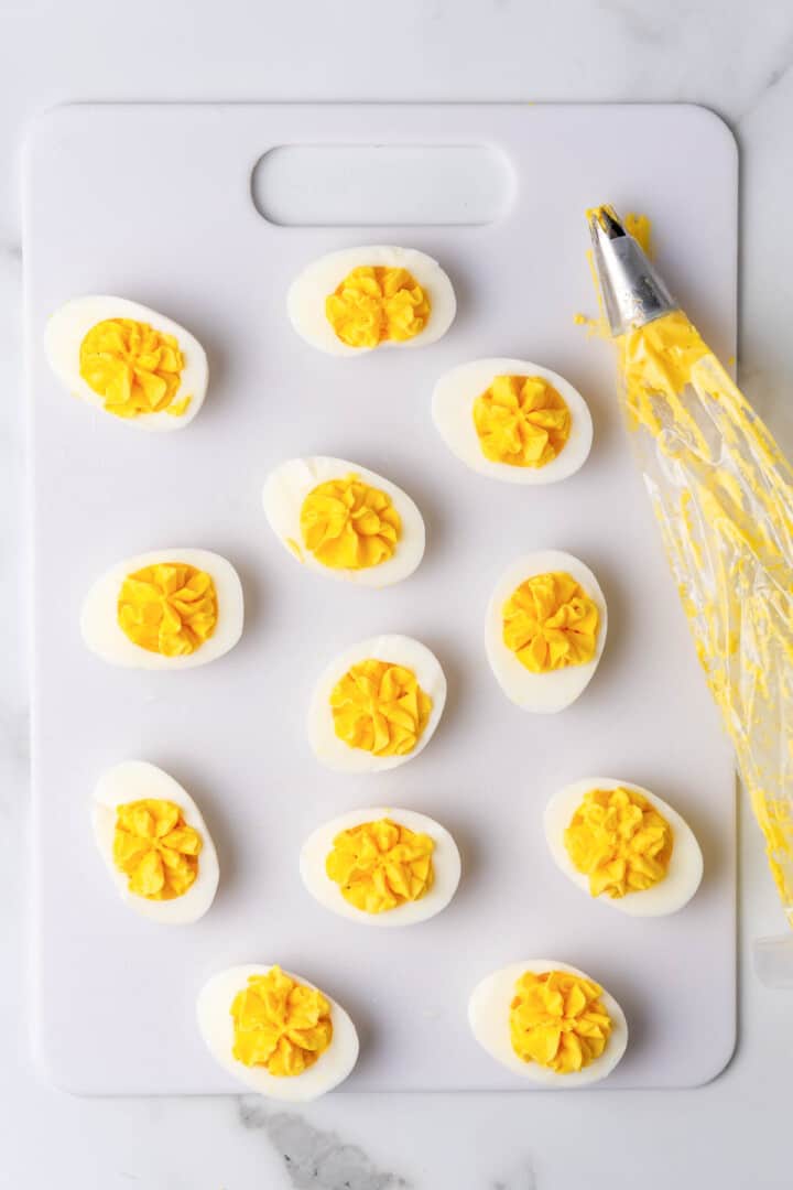 using a piping bag to fill the deviled eggs.