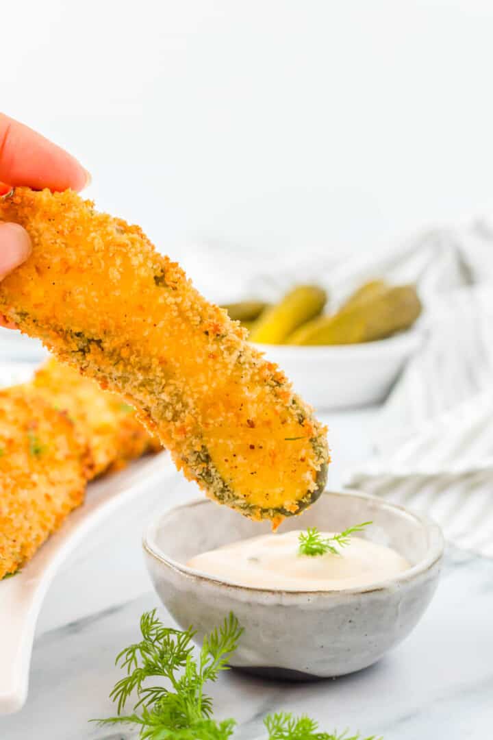 dipping the fried pickle in ranch dressing.