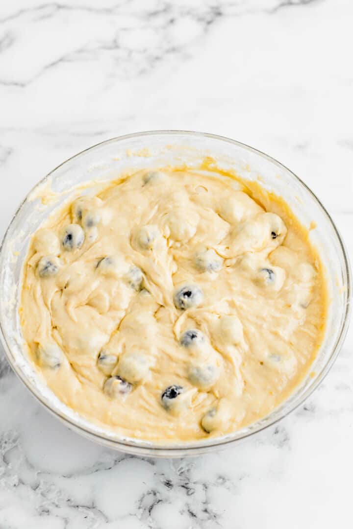 adding in dry ingredients to the wet ingredients and blueberries