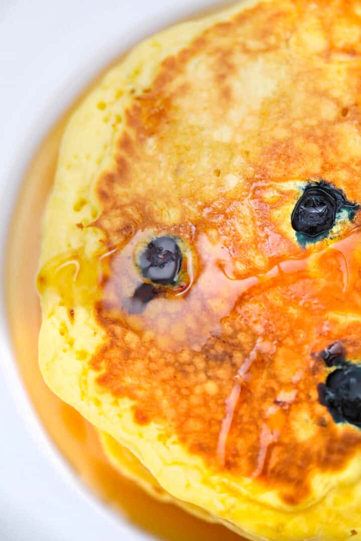 closeup of blueberry pancakes topped with syrup.