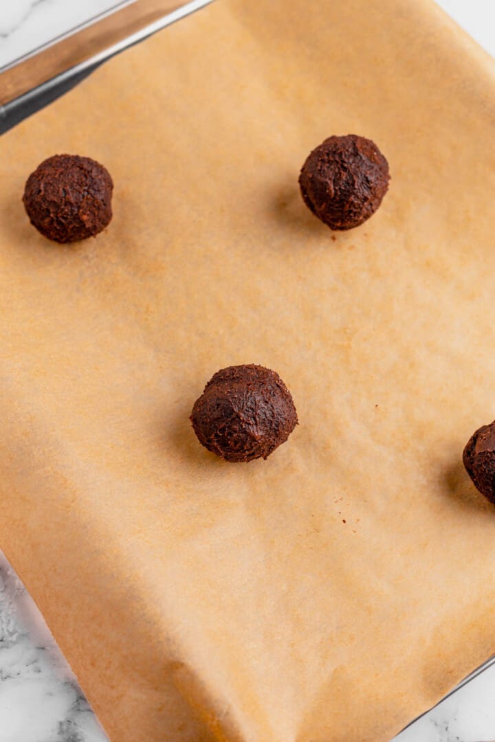 cookie dough balls on baking sheet with parchment paper