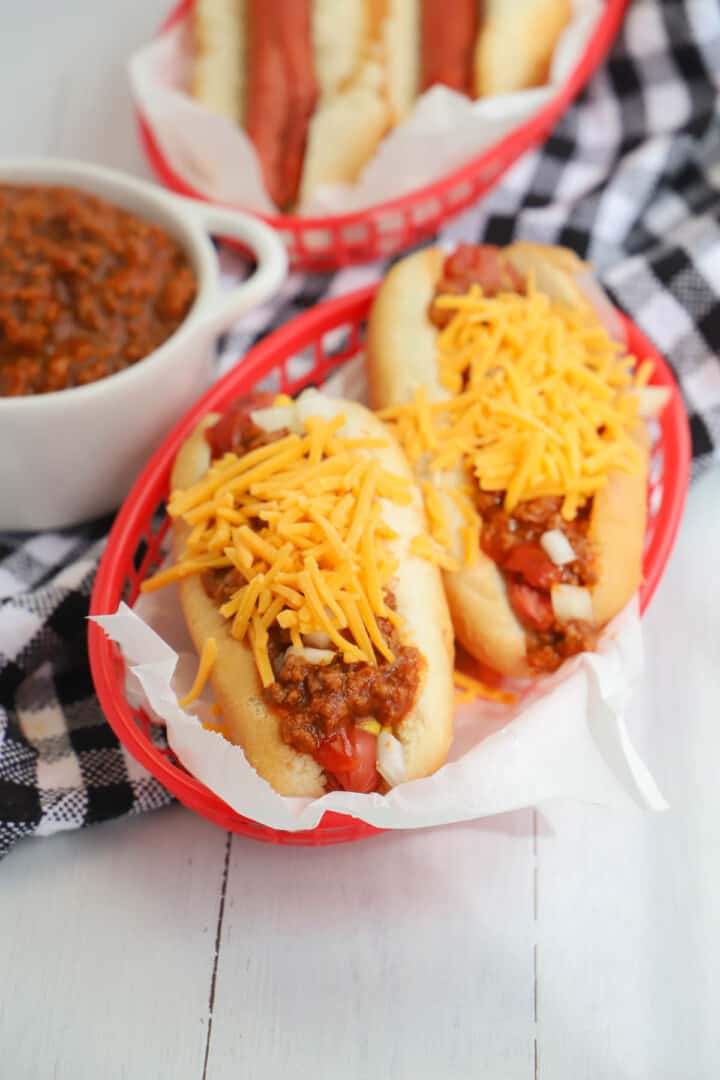 closeup of hot dogs covered in chili and topped with cheese