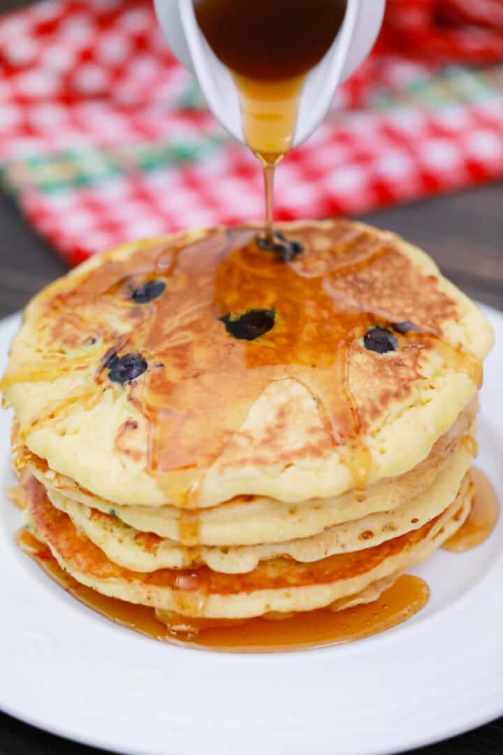 pouring syrup on top of the stacked pancakes