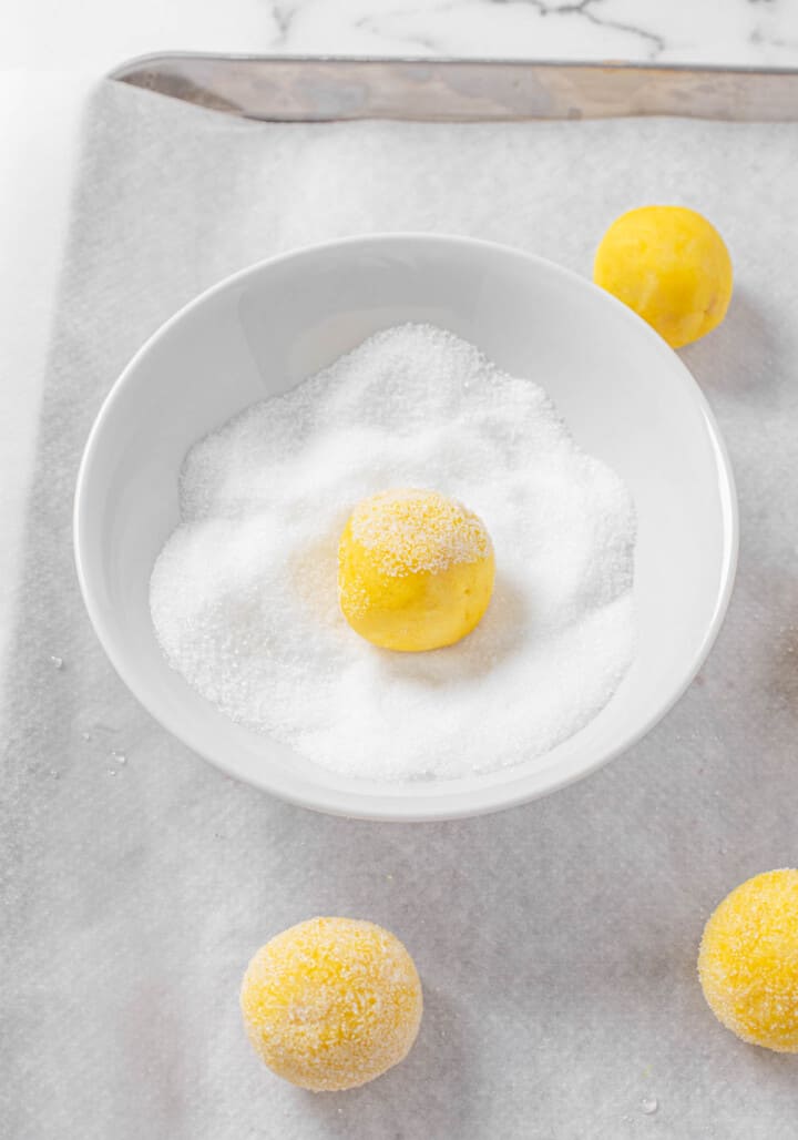 rolling cookie dough balls in sugar before baking