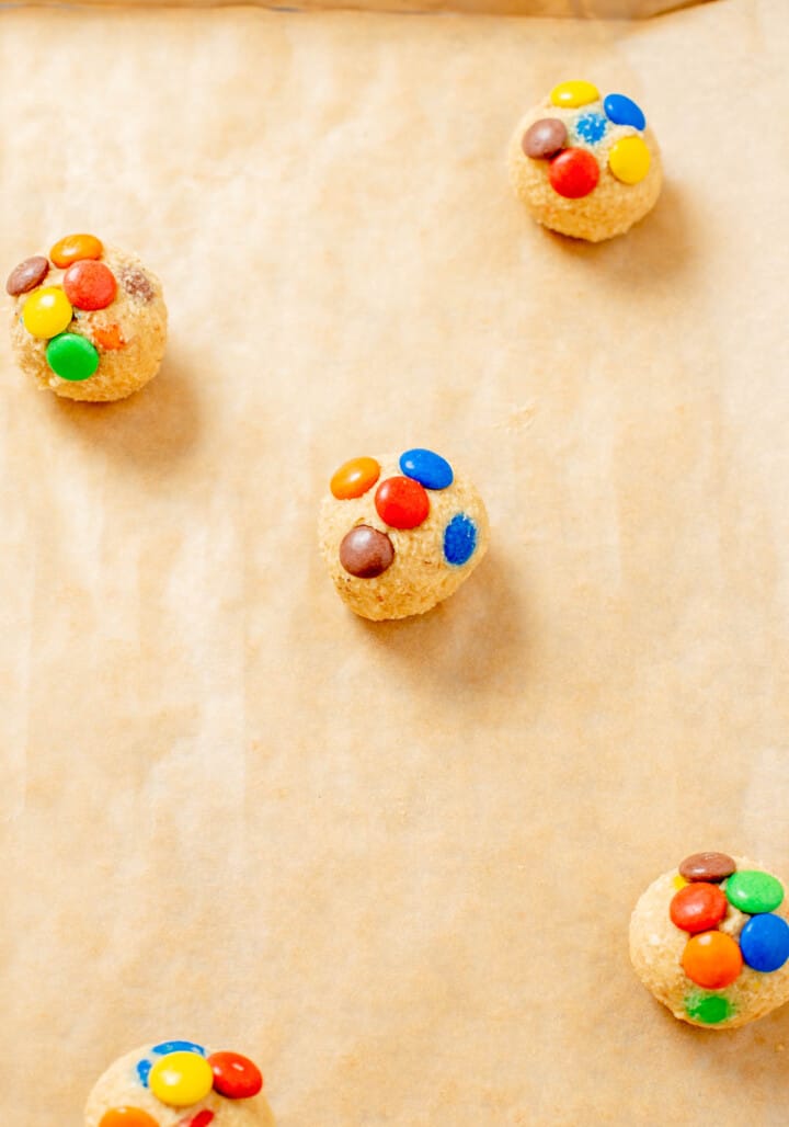 putting cookie dough balls on baking sheet with parchment paper