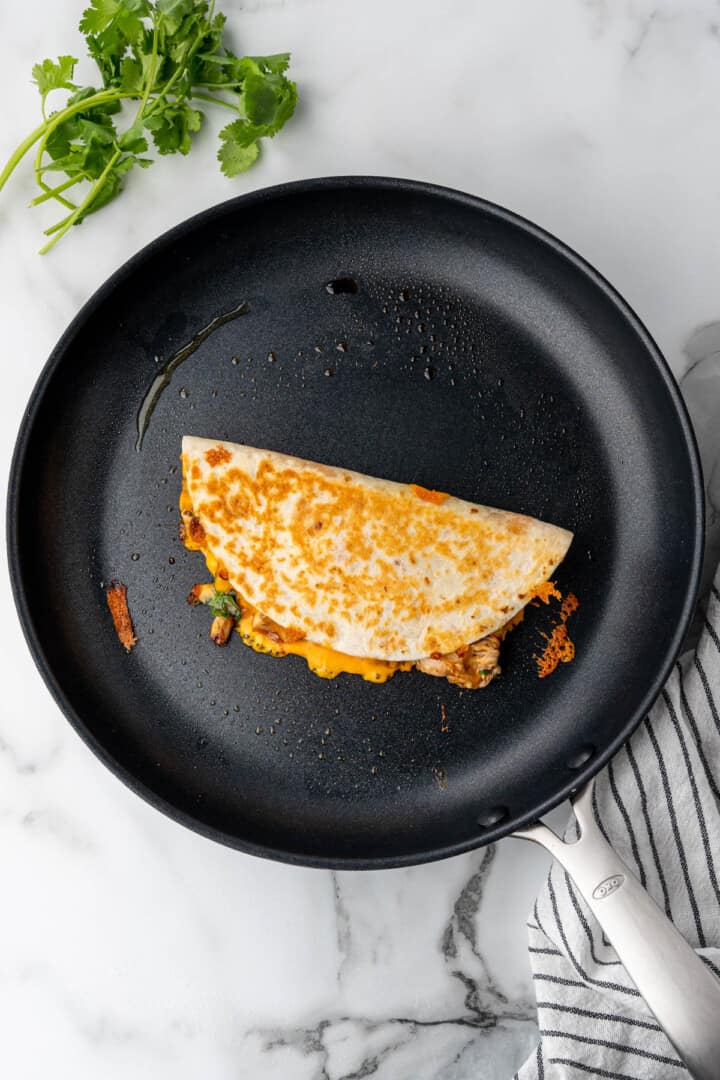 flipped quesadilla on pan cooking