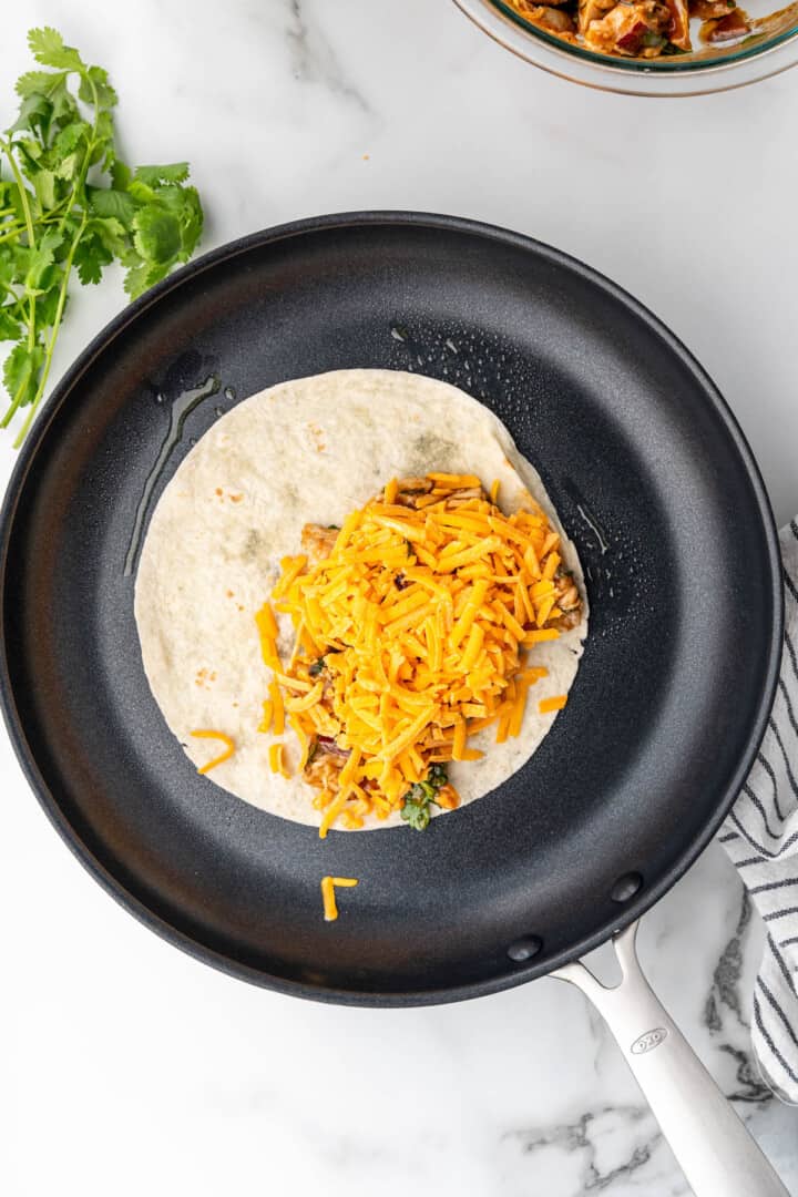 tortilla on pan filled with bbq chicken and cheese