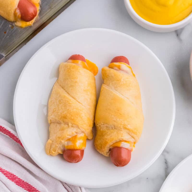 top view of two finishes hot dogs on a plate with mustard