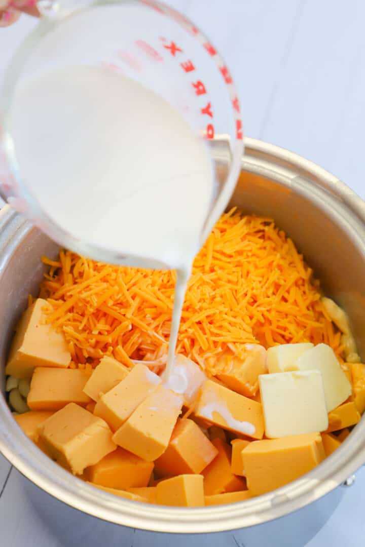 pouring half and half into the mac and cheese. 