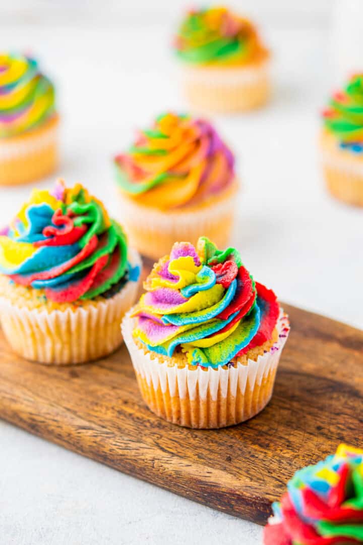 rainbow cupcakes on wooden serving board