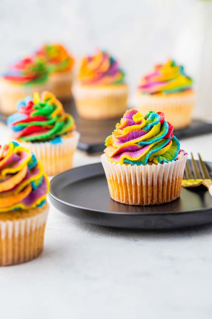 rainbow cupcakes on black plate.