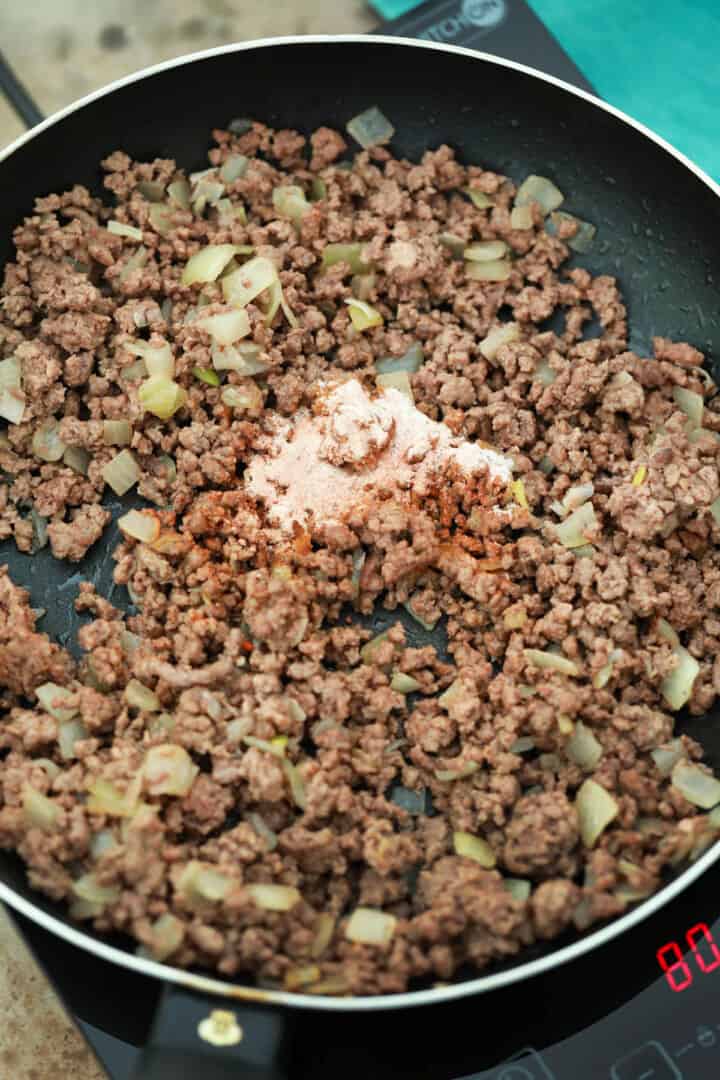 adding the spices to the ground beef