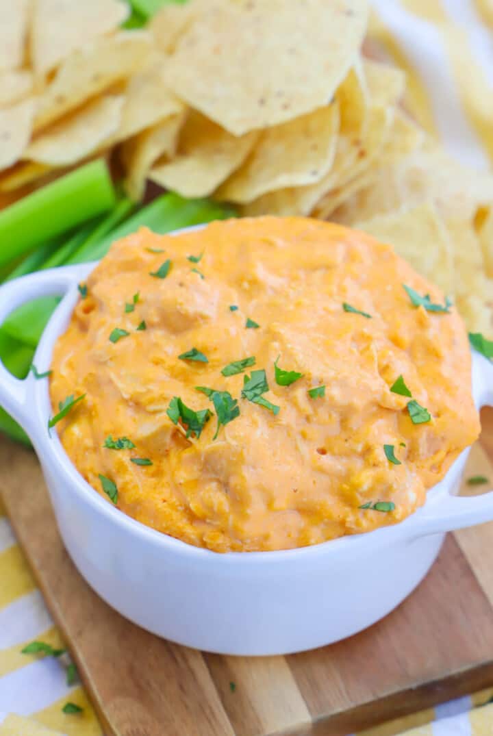 Slow Cooker Buffalo Chicken Dip in white bowl with chips and celery.