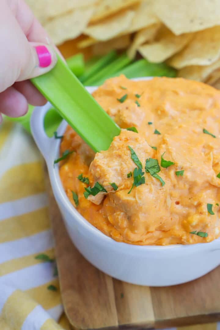 using celery to scoop out Buffalo Chicken dip.