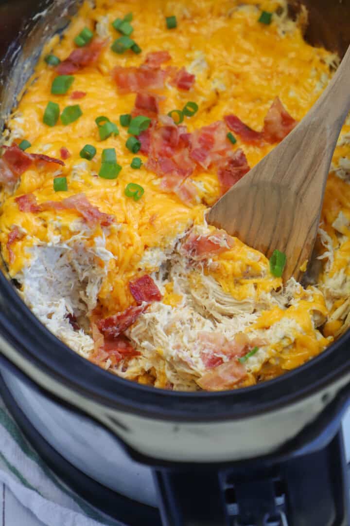 Slow Cooker Crack Chicken being mixed with a wooden spoon.