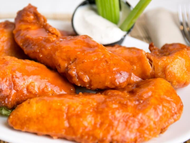 Buffalo Chicken Tenders on white plate with ranch and celery.