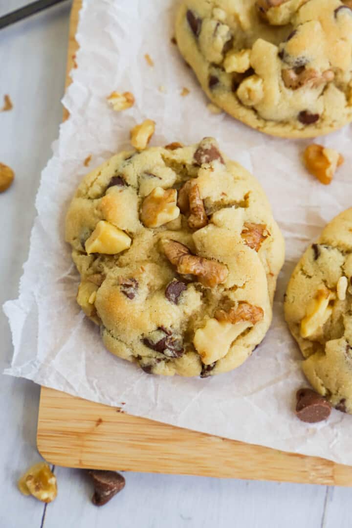 close up of walnut chocolate chip cookies on wooden board