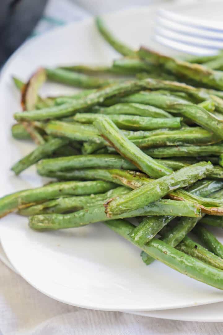 air fryer green beans on white plates close up.