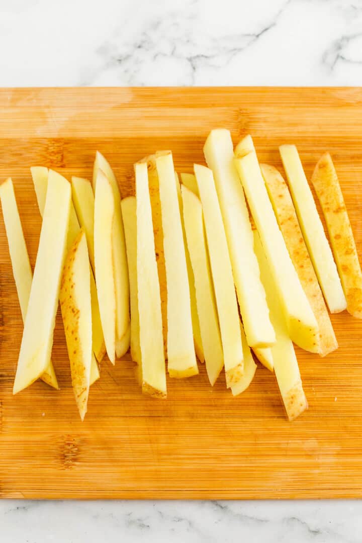 sliced French fries on wood cutting board.