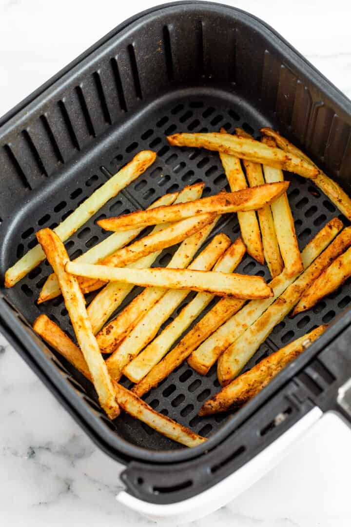 cooked French fries in air fryer basket.