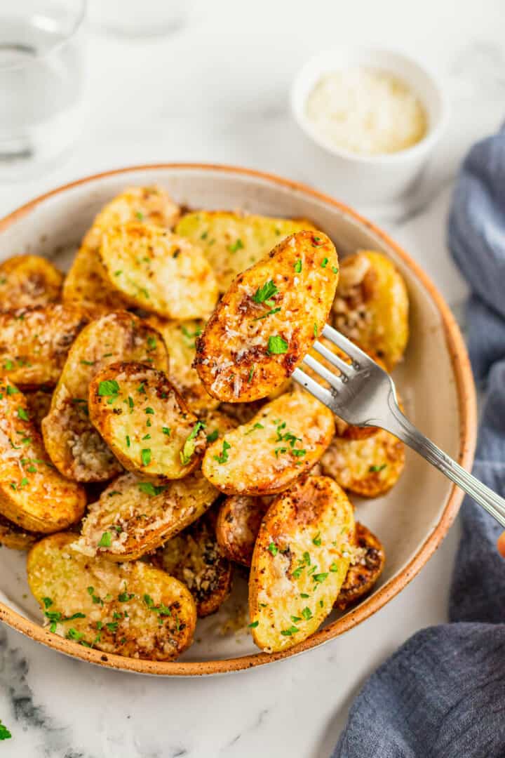 using a fork to get a potato from the serving bowl.