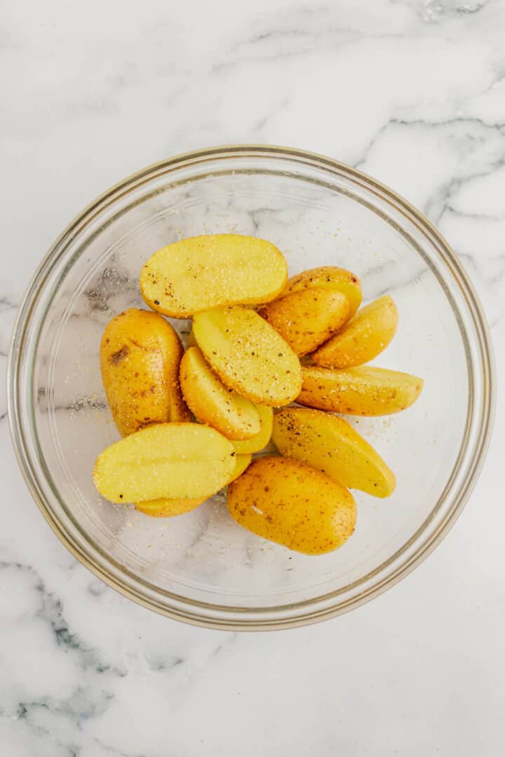 halved potatoes in glass bowl seasoned.