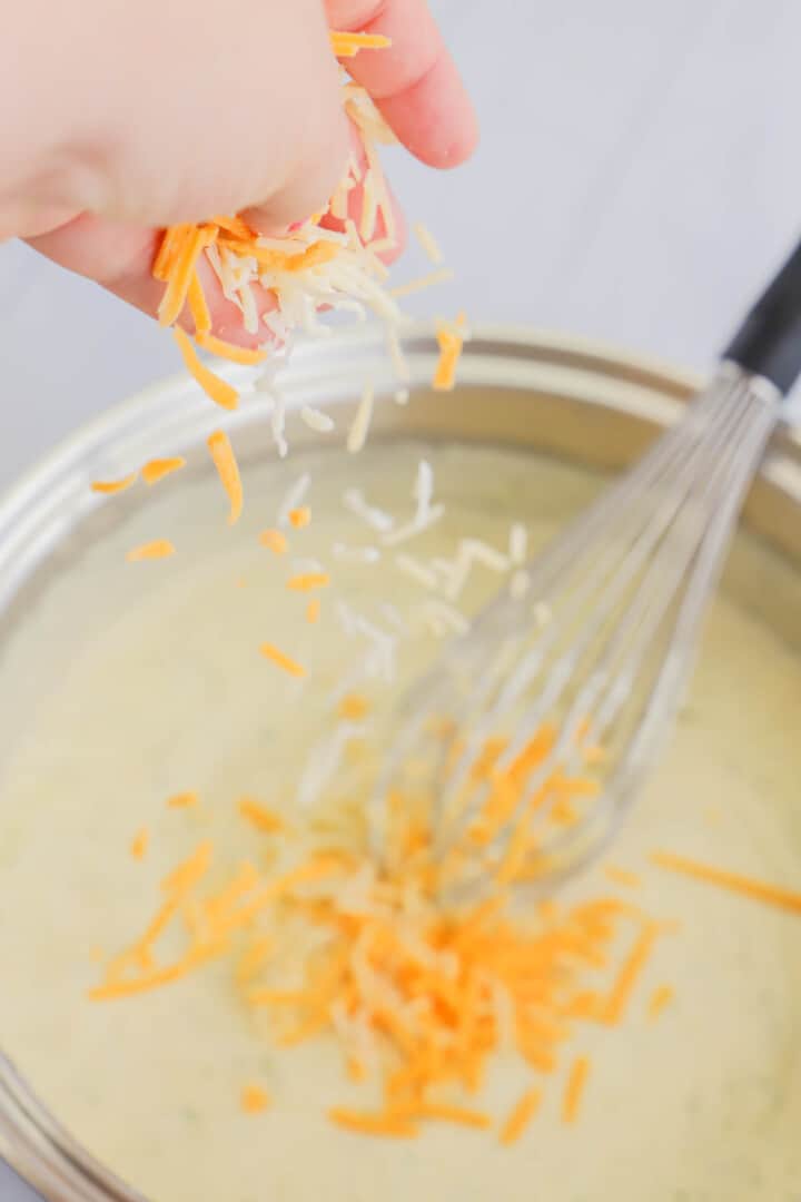 adding cheese to the cheese sauce.