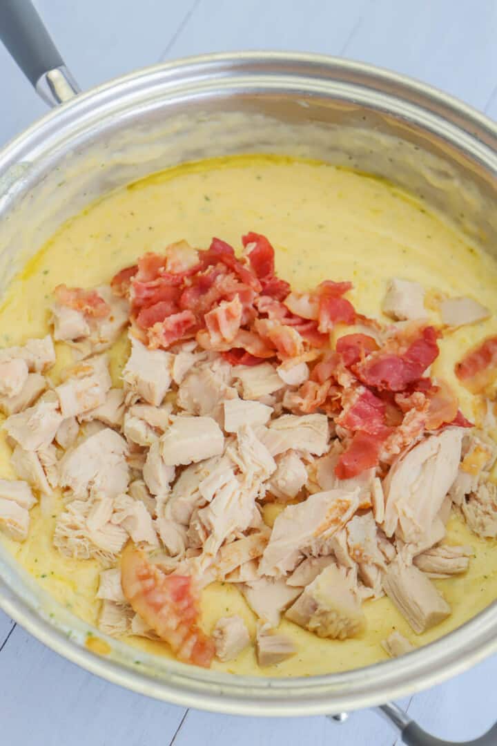 adding chicken and bacon to the cheese sauce.