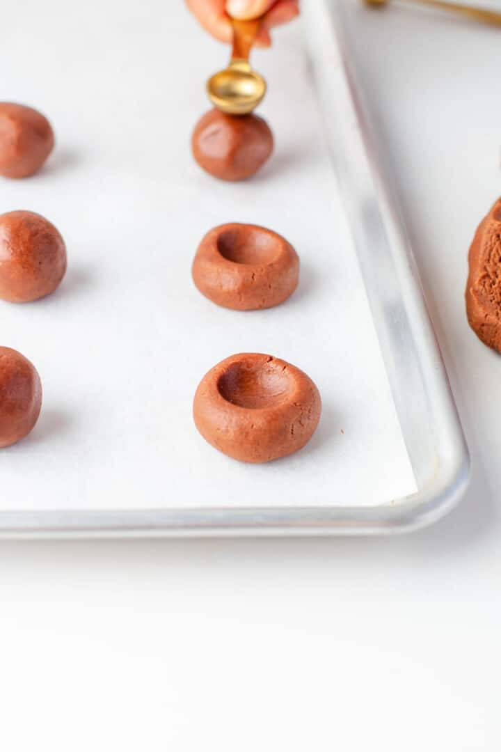 thumbprint cookie dough balls on baking sheet.